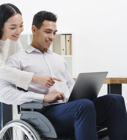 close-up-woman-standing-businessman-sitting-wheelchair-showing-something-laptop close-up-woman-standing-businessman-sitting-wheelchair-showing-something-laptop