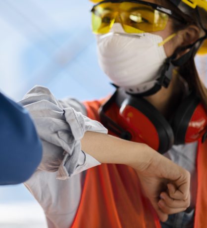 colleagues-with-safety-equipment-touching-elbow colleagues-with-safety-equipment-touching-elbow